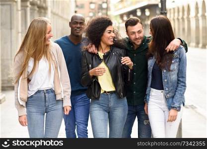 Multi-ethnic group of young people having fun together outdoors in urban background. group of people walking together. Group of friends having fun together outdoors