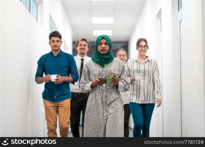 Multi-ethnic startup business team walking through the hallway of the building while coming back from a coffee break. High-quality photo. Multi-ethnic startup business team walking through the hallway of the building while coming back from a coffee break