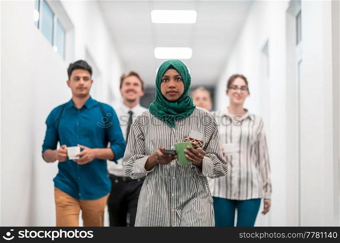 Multi-ethnic startup business team walking through the hallway of the building while coming back from a coffee break. High-quality photo. Multi-ethnic startup business team walking through the hallway of the building while coming back from a coffee break