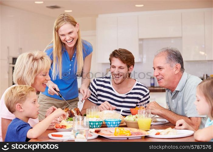 Multi Generation Family Enjoying Meal At Home Together