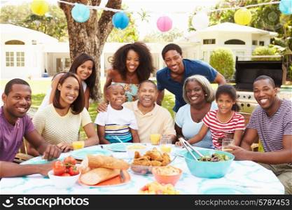 Multi Generation Family Enjoying Meal In Garden Together