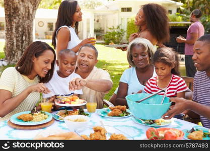 Multi Generation Family Enjoying Meal In Garden Together