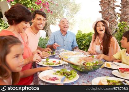 Multi Generation Family Enjoying Meal On Terrace Together
