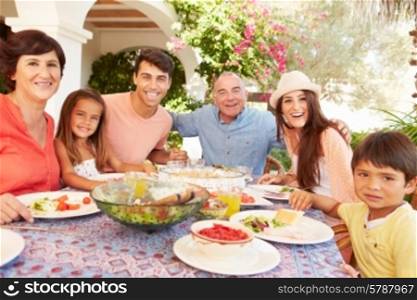 Multi Generation Family Enjoying Meal On Terrace Together