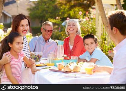 Multi-Generation Family Enjoying Outdoor Meal In Garden