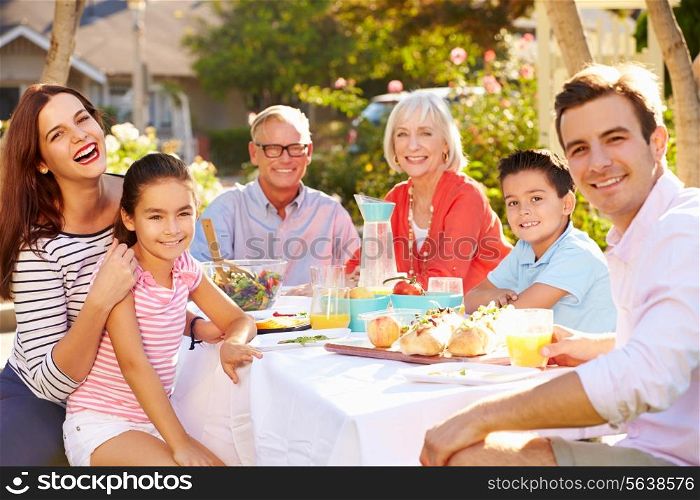 Multi-Generation Family Enjoying Outdoor Meal In Garden