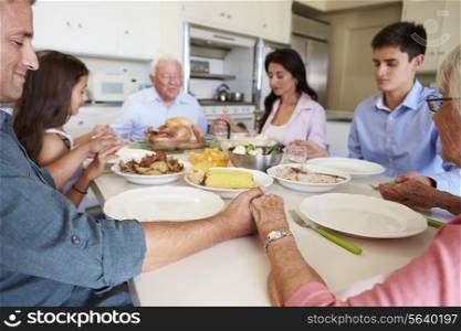 Multi-Generation Family Saying Prayer Before Eating Meal