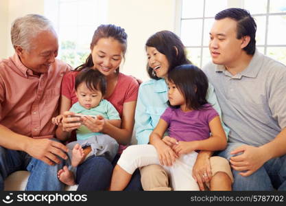 Multi Generation Family Sitting On Sofa With Mobile Phone