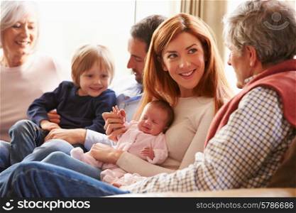 Multi Generation Family Sitting On Sofa With Newborn Baby