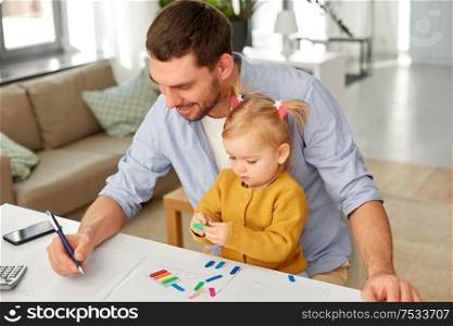 multi-tasking, freelance and fatherhood concept - working father with baby daughter at home office. working father with baby daughter at home office