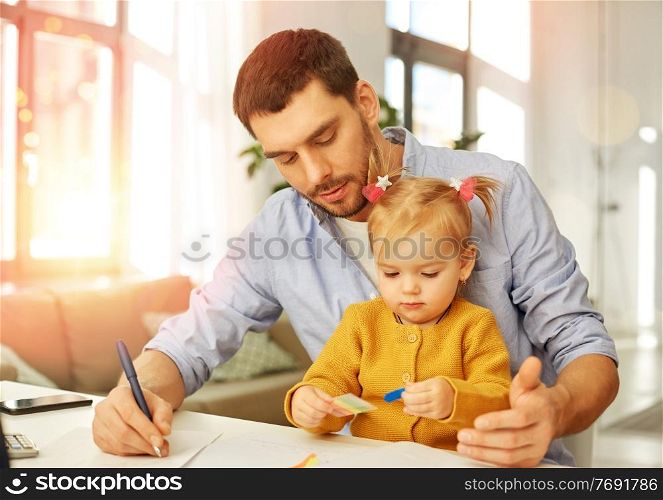 multi-tasking, freelance and fatherhood concept - working father with baby daughter at home office. working father with baby daughter at home office