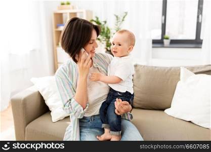 multi-tasking, freelance and motherhood concept - mother with baby son calling on smartphone at home. mother with baby son calling on smartphone