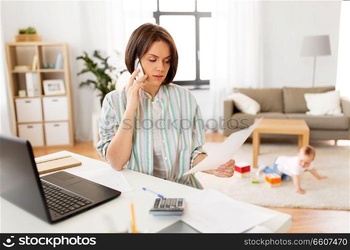 multi-tasking, freelance and motherhood concept - working mother with papers calling on smartphone and baby boy playing with laptop computer at home. working mother with baby calling on smartphone