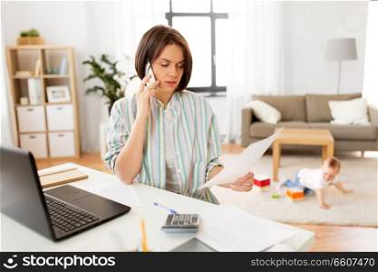 multi-tasking, freelance and motherhood concept - working mother with papers calling on smartphone and baby boy playing with laptop computer at home. working mother with baby calling on smartphone