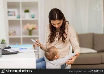 multi-tasking, freelance, family and technology concept - baby boy disturbing mother working at home. baby boy disturbing mother working at home