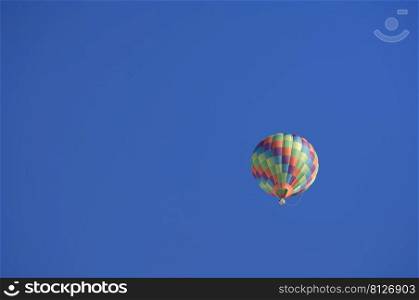 Multicolor hot air balloon in the blue sky with copy space