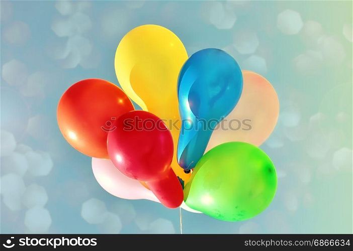 Multicolored balloons against the sky with bright sun, vintage toning