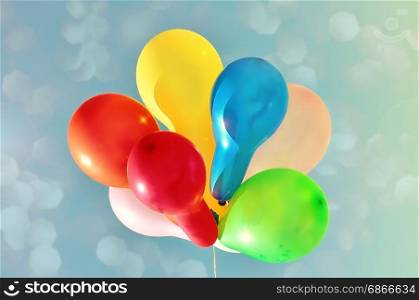 Multicolored balloons against the sky with bright sun, vintage toning