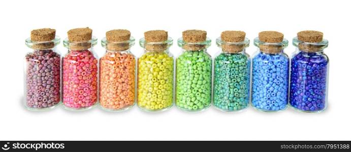Multicolored beads in small glass jars on a white background