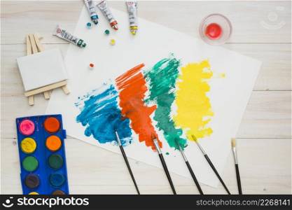 multicolored brushstroke white page with painting equipment wooden table