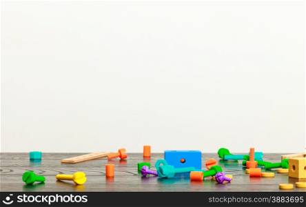 multicolored building blocks toy on wooden table empty interior white wall background