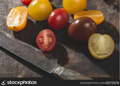 Multicolored cherry tomatoes on wood and knife