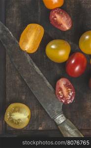 Multicolored cherry tomatoes on wood and knife