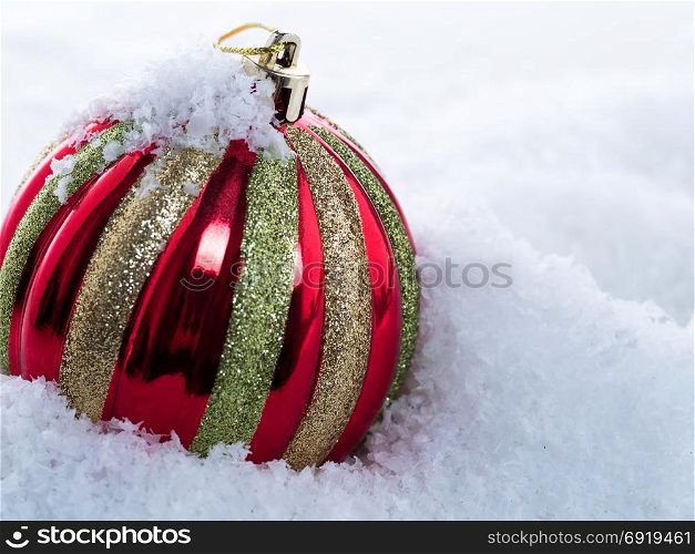 Multicolored Christmas ball in the snow