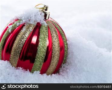 Multicolored Christmas ball in the snow