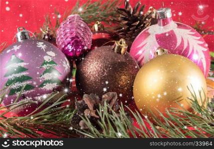 Multicolored Christmas balls and pine cone.. Christmas balls lying on spruce branches. Blurred background