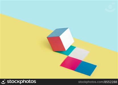 Multicolored cube leaves marks on a yellow and blue background. Abstract minimal concept. Isometric layout with copy space. Geometric shape. Multicolored cube leaves marks on a yellow and blue background