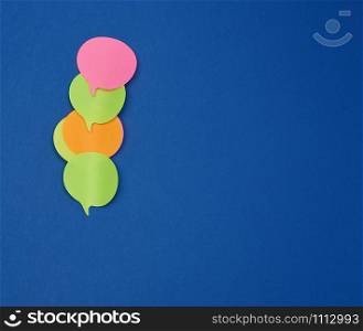 multicolored empty paper stickers in the form of clouds on a blue background, copy space