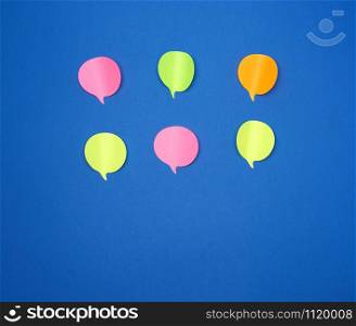 multicolored empty paper stickers in the form of clouds on a blue background, copy space