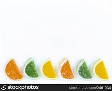 Multicolored marmalade citrus slices in sugar on a white background with copy space.. Multicolored marmalade citrus slices in sugar on white background with copy space.