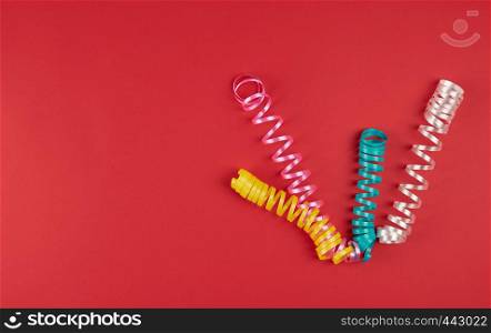 multicolored paper serpentine on red paper, festive background, copy space