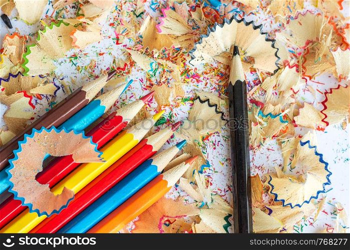 Multicolored pencils and shavings from pencils on a white background