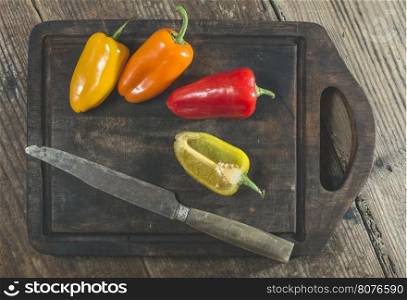 Multicolored peppers on wood and knife