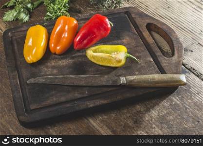 Multicolored peppers on wood and knife