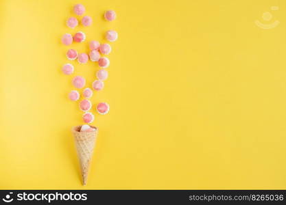 Multicolored pink and white meringues in waffle cookies on a yellow background. Multicolored pink and white meringues in waffle cookies scattered on a yellow background