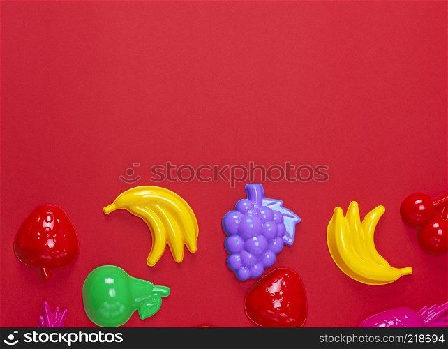 multicolored plastic childrens toys in the form of fruit on a red background
