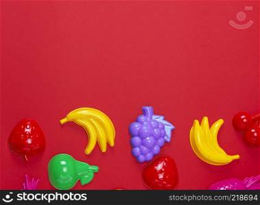 multicolored plastic childrens toys in the form of fruit on a red background