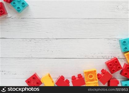 Multicolored Plastic constructor bricks on white wooden background. Popular toys. Free space for text. Plastic constructor bricks on white wooden background. Popular toys. Free space for text