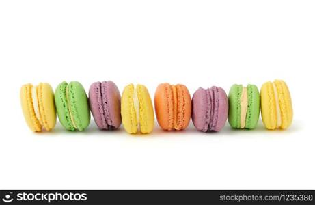 multicolored round baked macaroon cakes isolated on a white background, dessert stands in a row
