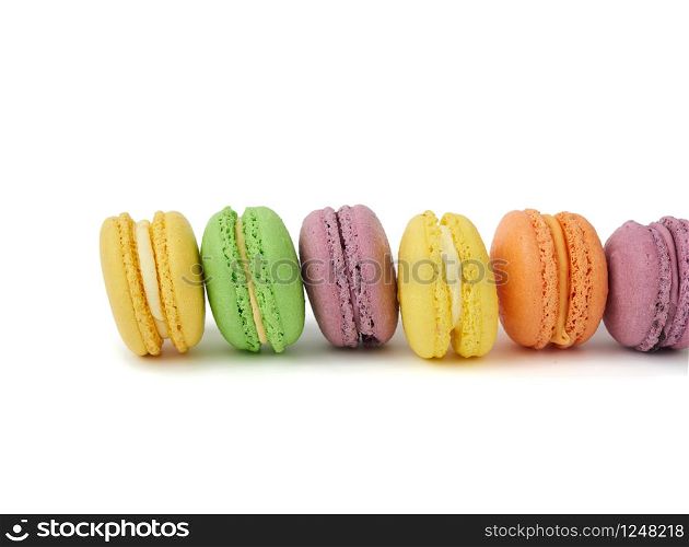 multicolored round baked macaroon cakes isolated on a white background, dessert stands in a row