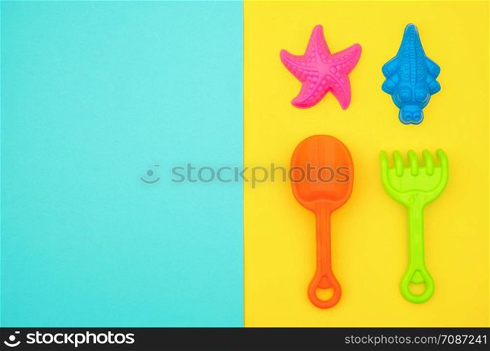 Multicolored set children&rsquo;s toys for summer games in sandbox or on sandy beach on blue yellow background with copy space. Creative top view Flat lay Concept. Template for your text or design.. Multicolored set children&rsquo;s toys for summer games in sandbox or on sandy beach on blue yellow background with copy space. Top view Flat lay Concept. Template for your text or design