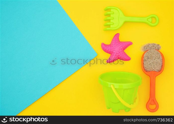 Multicolored set children's toys for summer games in sandbox or on sandy beach on blue yellow background with copy space. Creative top view Flat lay Concept. Template for your text or design.. Multicolored set children's toys for summer games in sandbox or on sandy beach on blue yellow background with copy space. Top view Flat lay Concept. Template for your text or design