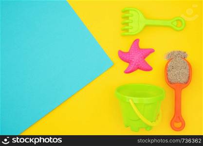 Multicolored set children's toys for summer games in sandbox or on sandy beach on blue yellow background with copy space. Creative top view Flat lay Concept. Template for your text or design.. Multicolored set children's toys for summer games in sandbox or on sandy beach on blue yellow background with copy space. Top view Flat lay Concept. Template for your text or design