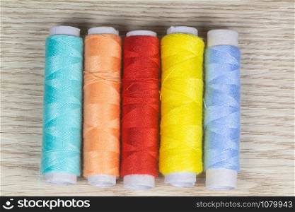 Multicolored sewing threads on wooden background