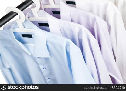 Multicolored shirts on plastic hangers, white background