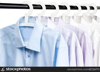 Multicolored shirts on plastic hangers, white background